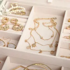 Elegancka szkatułka na biżuterię, idealna, by dowiedzieć się, jak przechowywać kolczyki i inne błyskotki. Złote naszyjniki, kolczyki i pierścionki.