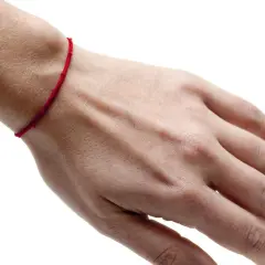 Czerwona nitka na nadgarstku symbolizuje ochronę i szczęście. To amulet, który ma odpędzać złe moce i przyciągać pozytywną energię.