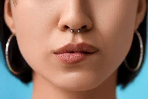 Zbliżenie na usta i nos z kolczykiem w septum. Delikatne, naturalne usta i srebrny kolczyk w przegrodzie nosowej.