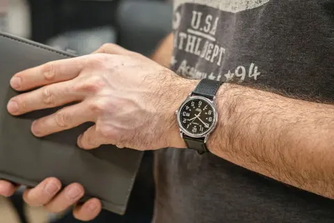 Mężczyzna z zegarkiem Timex, który jest znany z trwałości i przystępności. Klasyczny design, idealny na co dzień.