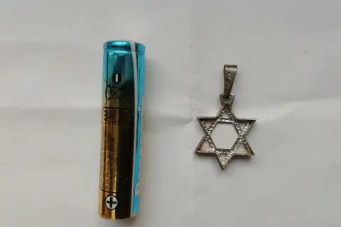 Obok baterii AAA leży srebrny wisiorek w kształcie Gwiazdy Dawida. To symbol, co oznacza przynależność i tożsamość.