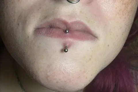 Labret co to? Kolczyk w wardze i pod nią, ozdobiony metalowymi kulkami. Skóra z piegami.