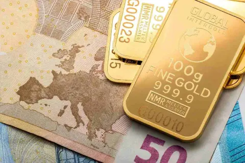 Sztabki złota LBMA o próbie 999.9 leżą na banknotach euro.