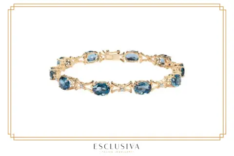 Złota bransoletka z niebieskimi kamieniami i diamentami. Taka żółta bransoletka symbolizuje elegancję i luksus.