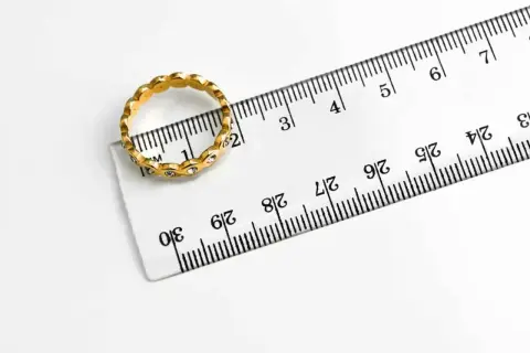 Złoty pierścionek z cyrkoniami obok linijki. Rozmiar 19 pierścionka ile to mm? Widać, że średnica wynosi ok. 19 mm.