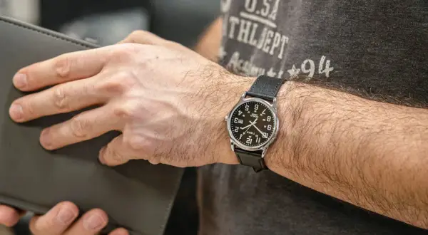 Mężczyzna z zegarkiem Timex, który jest znany z trwałości i przystępności. Klasyczny design, idealny na co dzień.
