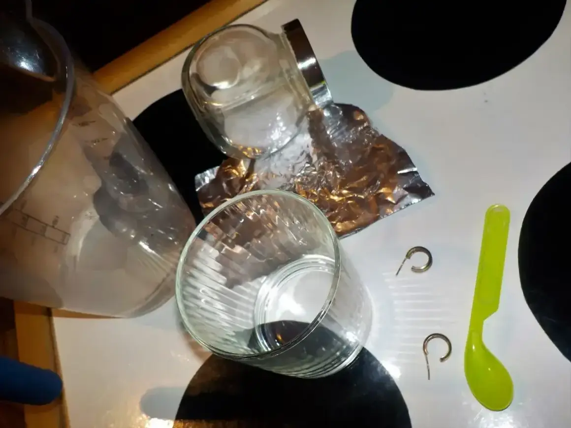 Przygotowania do czyszczenia złota folią aluminiową: szklanki, słoik, folia, łyżeczka i kolczyki.