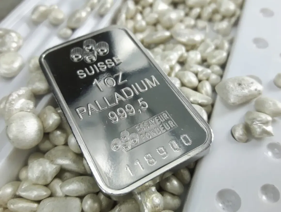 Sztabka palladu 1 uncja 999,5 na tle luźnych granulek tego cennego metalu.
