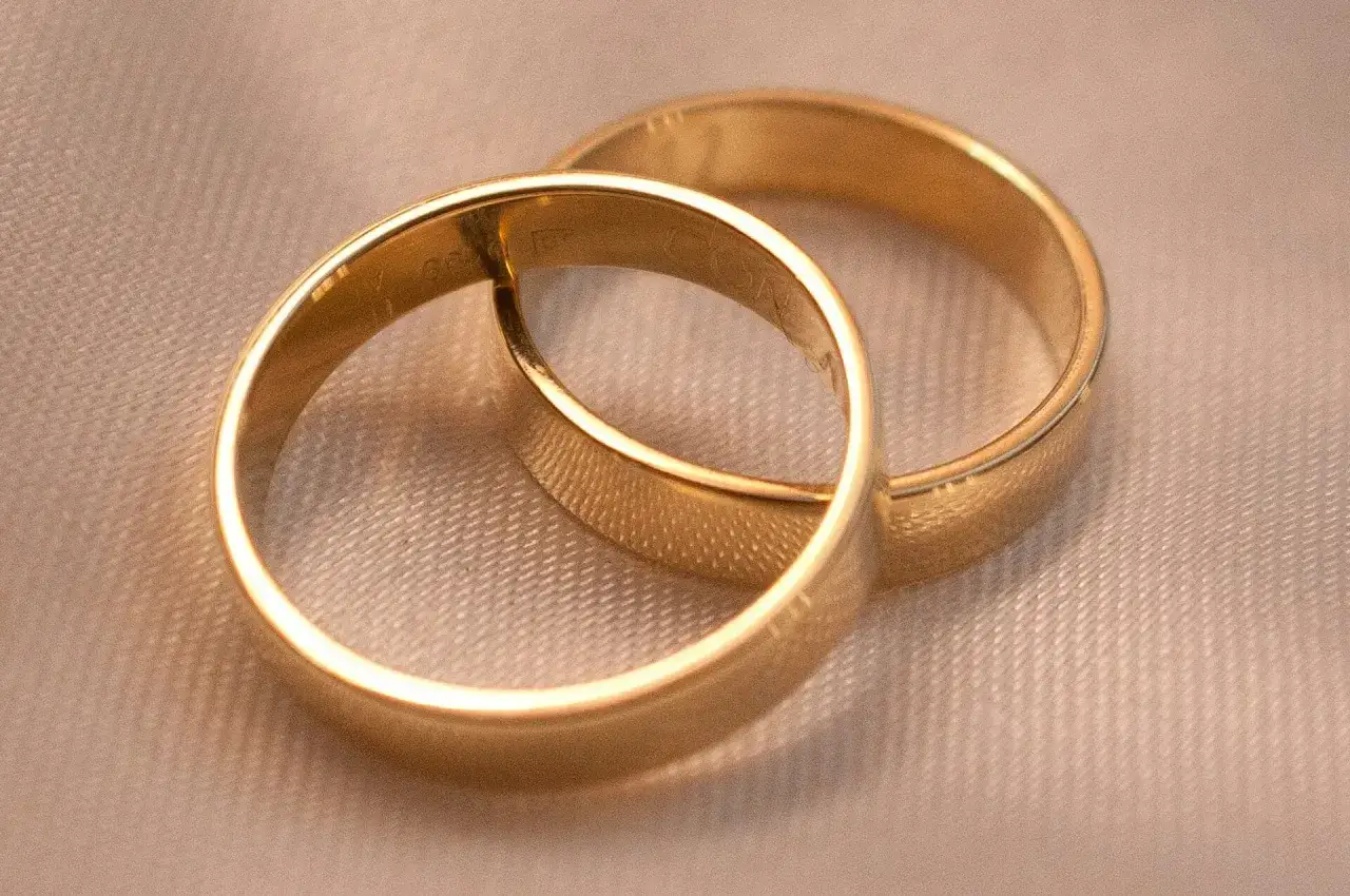 Dwie złote obrączki, symbol miłości. Zastanawiasz się, ile waży obrączka? Te są piękne i lśniące.