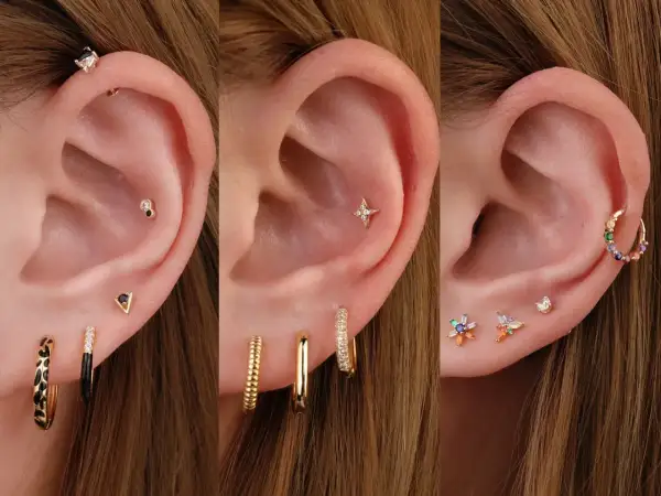 Trzy uszy z różnymi kolczykami: na pierwszym widać piercing tragus, na drugim gwiazdkę, a na trzecim kolorowe kamyczki.