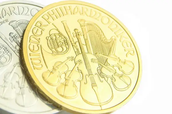 Złota moneta z instrumentami muzycznymi, w tym skrzypcami i harfą. Napis "Wiener Philharmoniker" otacza scenę.